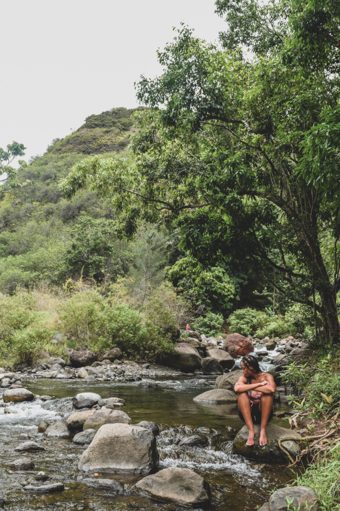 Girl sitting on a boulder in the Iao Valley Stream